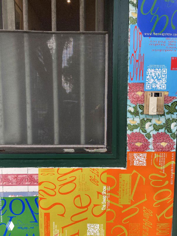 Крупный план двери и стены, покрытой рекламными наклейками и постерами The Swap Show, фрагмент уличной среды и визуальной кампании.