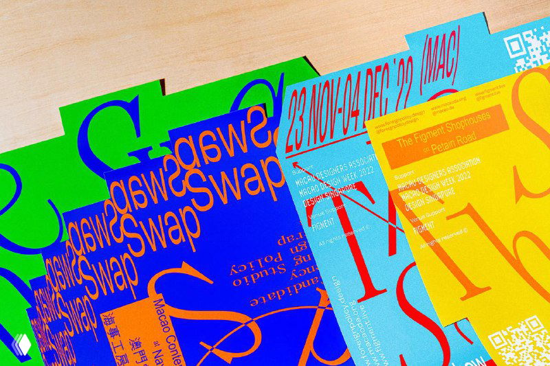 Пёстрые постеры The Swap Show в зелёно-синей палитре, фрагменты литер и декоративные элементы раскиданы по деревянной поверхности.