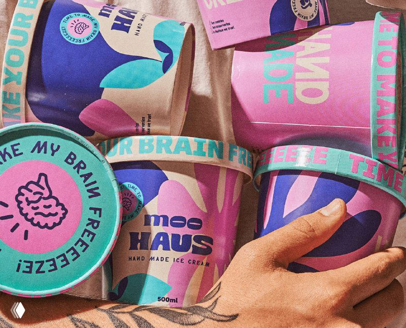 Несколько банок мороженого Moohaus на столе: пастельные ретро-узоры, декоративные шрифты и фирменные крышки с логотипом в кадре.