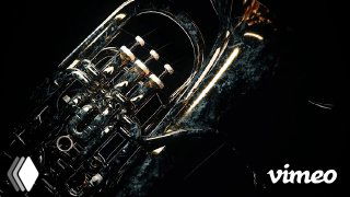 Часть духового музыкального инструмента в процессе разрушения: изломанные детали, винты и металлические отражения на тёмном фоне, художественный моушен.