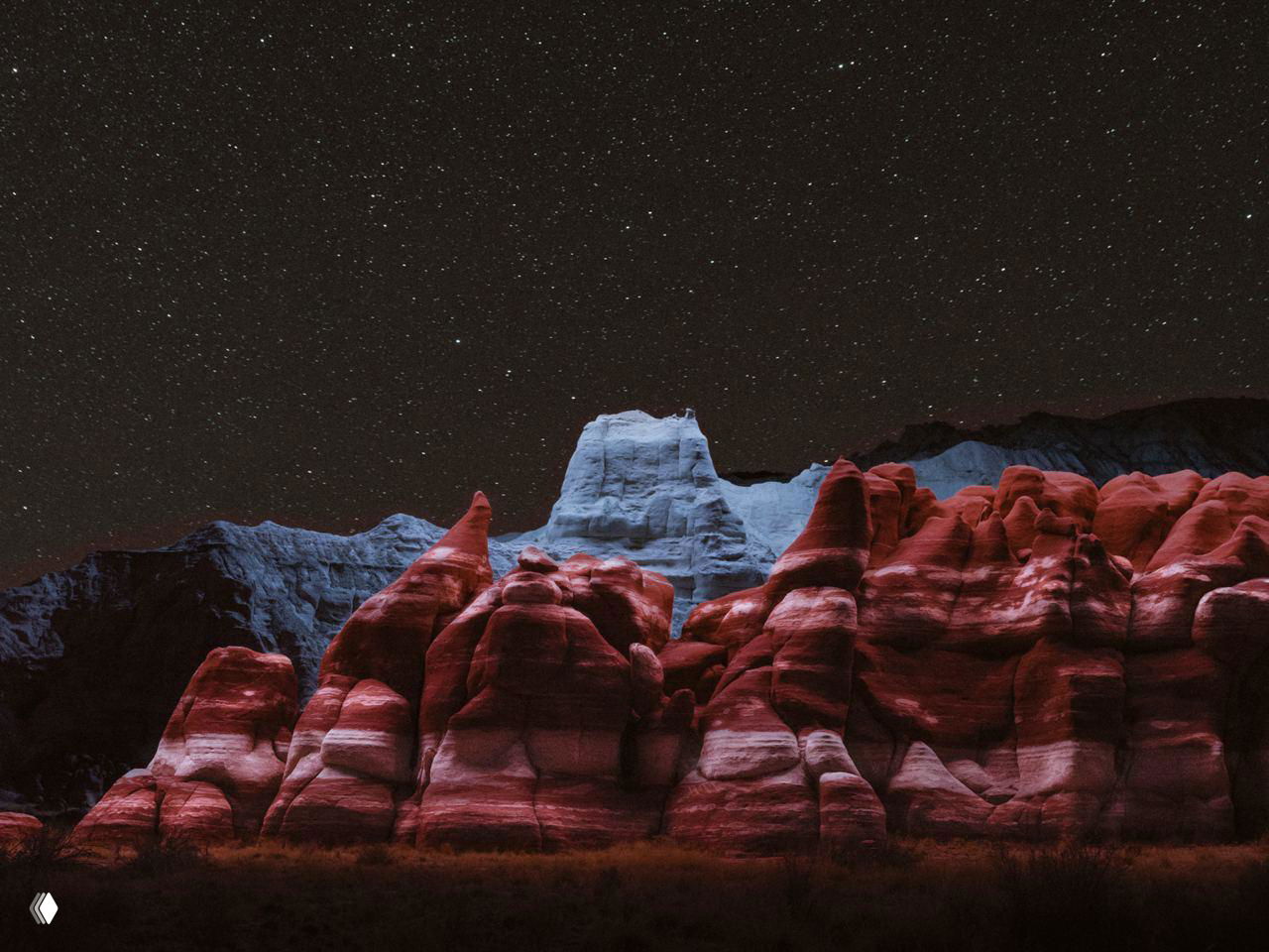 Ночной пейзаж с массивными каменными образованиями под звёздным небом, локальная подсветка создаёт театральный, «космический» эффект.