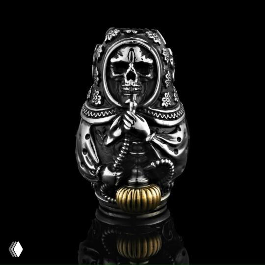 Матрешка-скелет — серебряная подвеска с чёрными патинами и золотым акцентом в основании, выразительная фактура, чёрный отражающий фон, показано крупным планом.