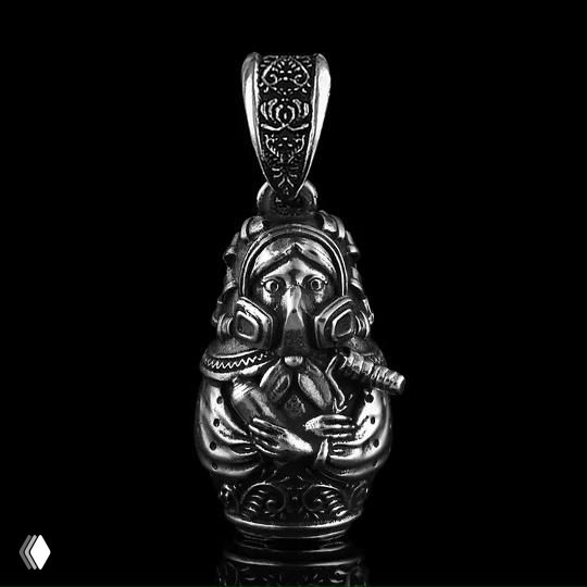 Подвеска в виде маленькой фигурки с трубкой и детальной гравировкой, серебро с глубокими тенями, чёрный отражающий фон, показано крупным планом.