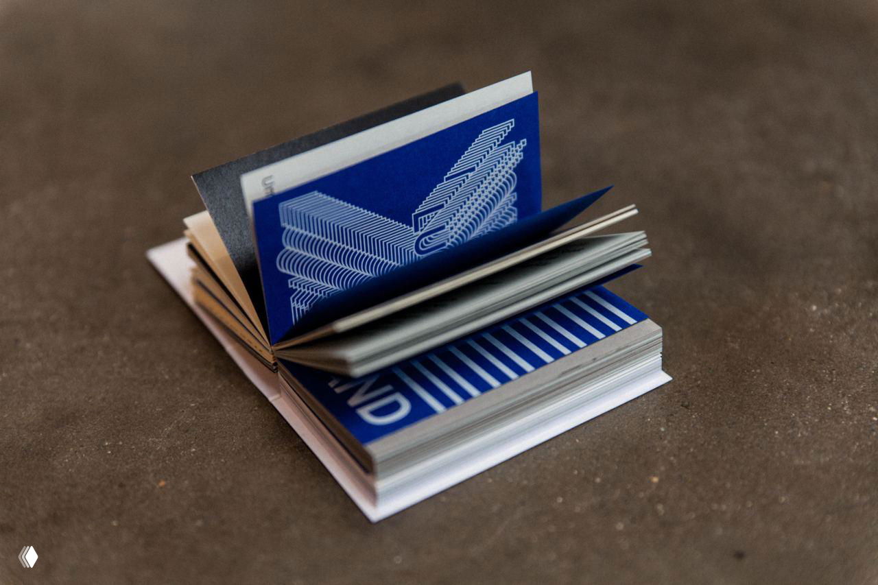 Разворот мини‑книги с немецкой фразой о паузе; фотография подчёркивает идею проекта — задуматься о коротких перерывах в повседневной жизни.