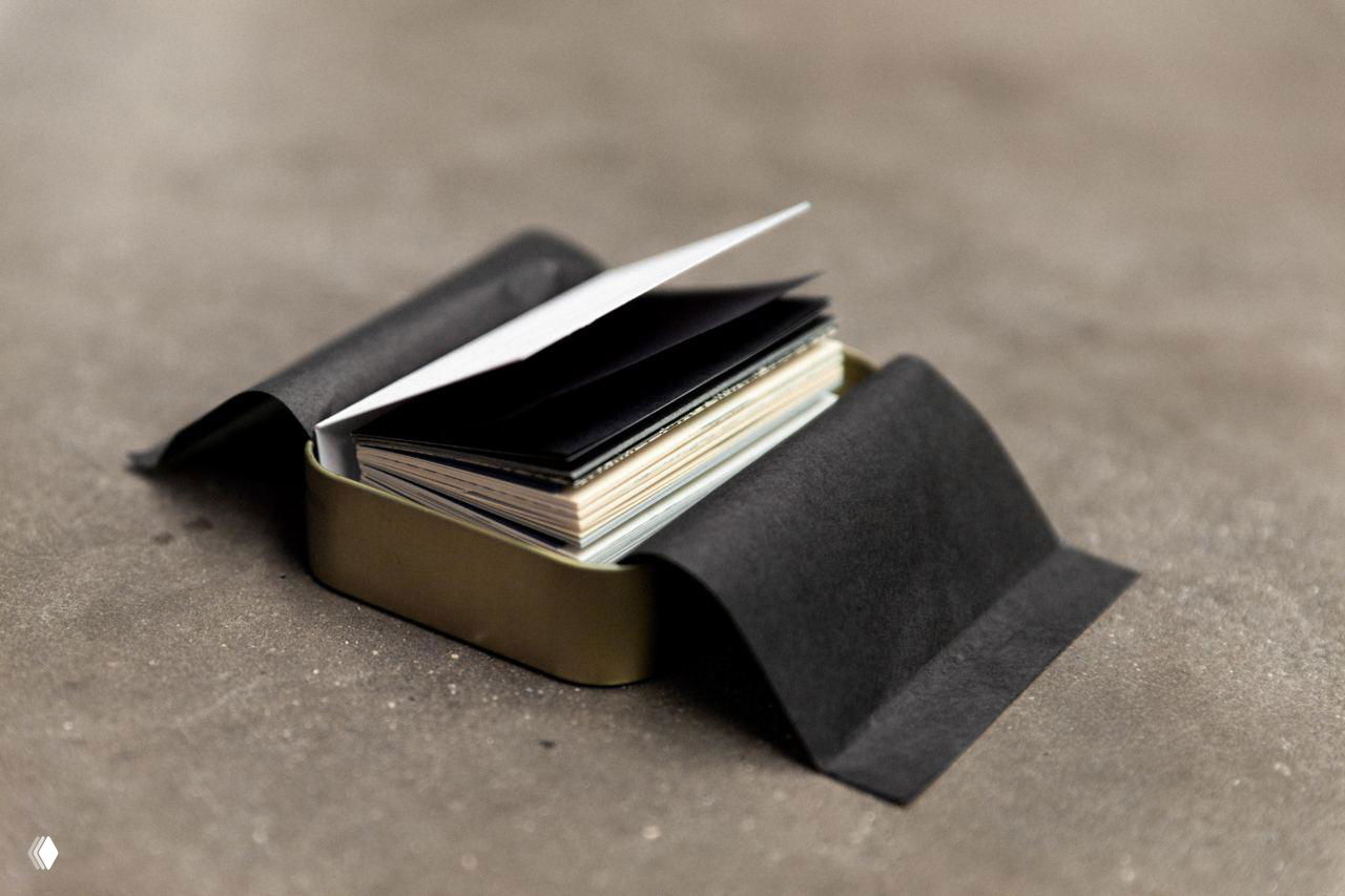 Жёстяная коробочка‑упаковка и мини‑книга внутри; снимок отражает упаковочную идею проекта — книга как пачка/ящичек для пауз.