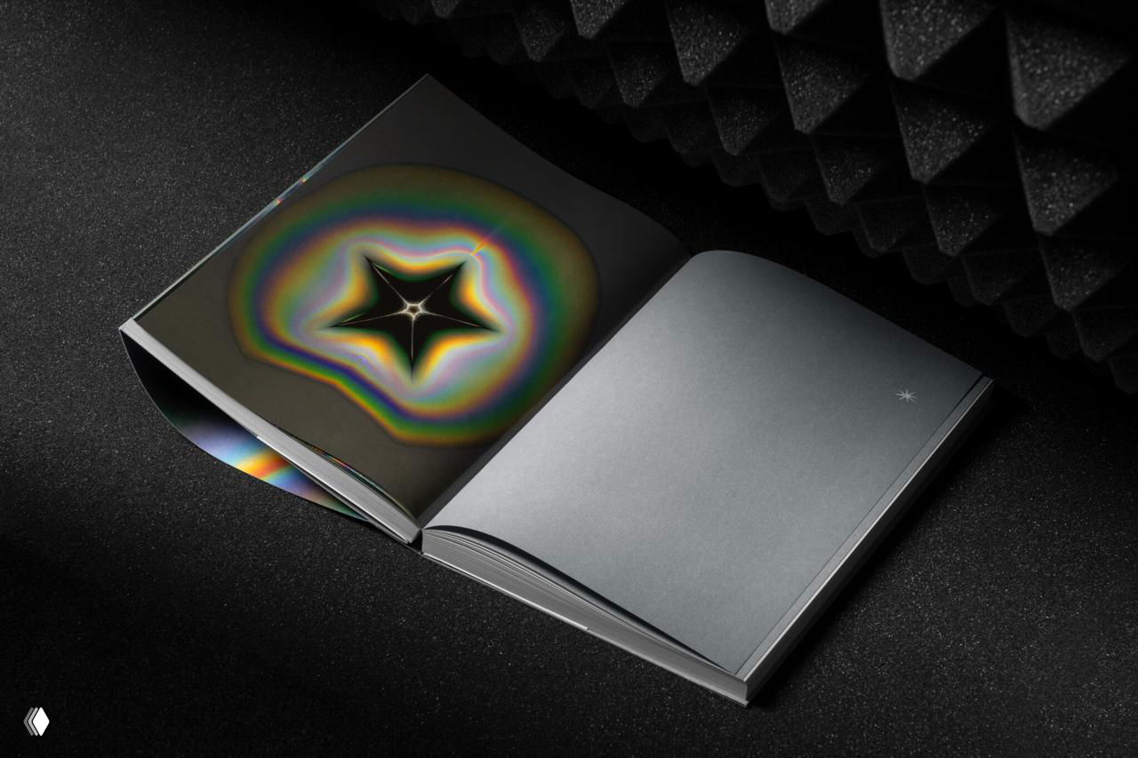 Каталог открыт на развороте с крупной звездообразной голографической иллюстрацией и маленькой белой звёздочкой в центре.