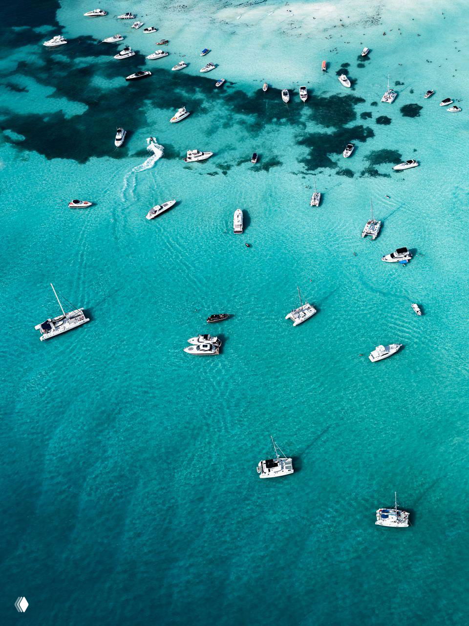Вертикальный кадр с большим количеством стоящих и движущихся лодок над бирюзовой поверхностью моря — воздушный план с глубиной.