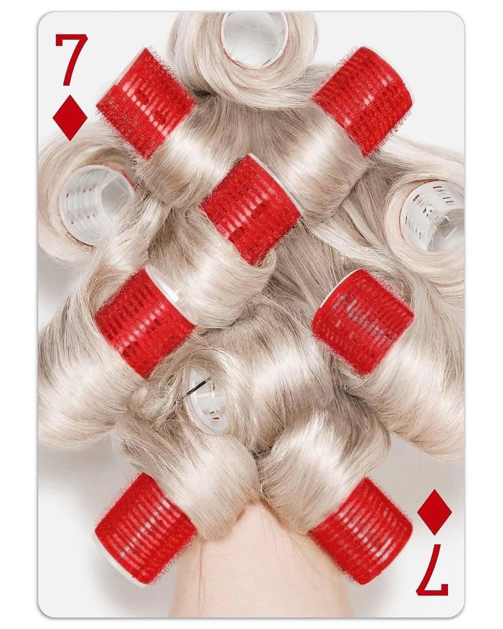 Карта с крупным планом волос и яркими красными бигуди, составленными в декоративный узор, трансформация бытового предмета в орнамент.