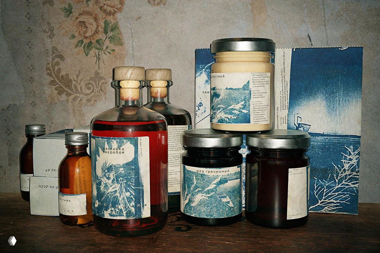 Фотография набора бутылочек и баночек с этикетками в сине-белой гамме, видна текстура бумаги и рустикальная деревянная поверхность под ними.