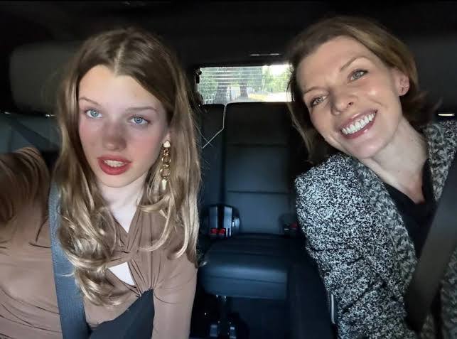 Женщина и девушка в автомобиле, обе улыбаются на переднем сиденье; фото походное, спонтанное, передвижной кадр из поездки.