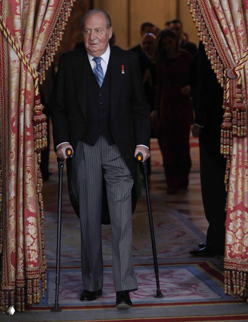 Пожилой мужчина в парадном костюме с двумя тростями выходит из-за портьер в богатом дворцовом интерьере, официальная сцена.