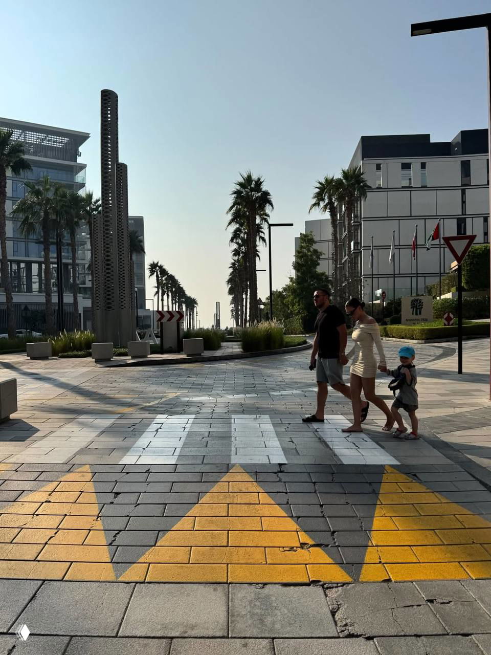 Оля Серябкина выходит из воды в чёрном купальнике на фоне крупных волн; пляжный кадр с акцентом на фигуру певицы и морской пейзаж.