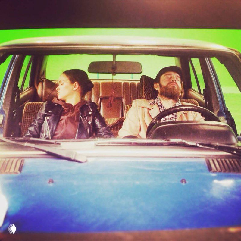 Искажённый глитч‑кадр из закулисья: актёры в автомобиле, разноцветные артефакты и эффект старой плёнки — редкий архивный снимок со съёмок.