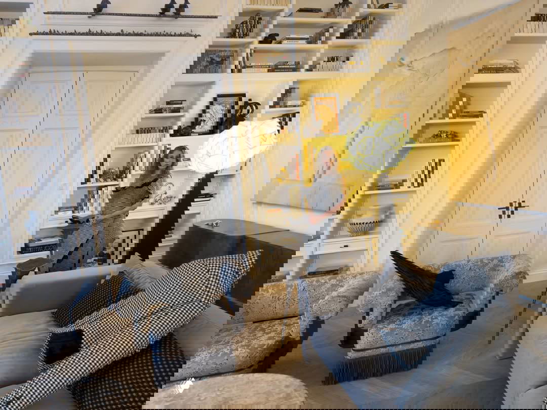 Гостиная с диваном, декоративными подушками в клетку, большим настольным светильником и картины на стене — элегантная эклектика и редкие материалы