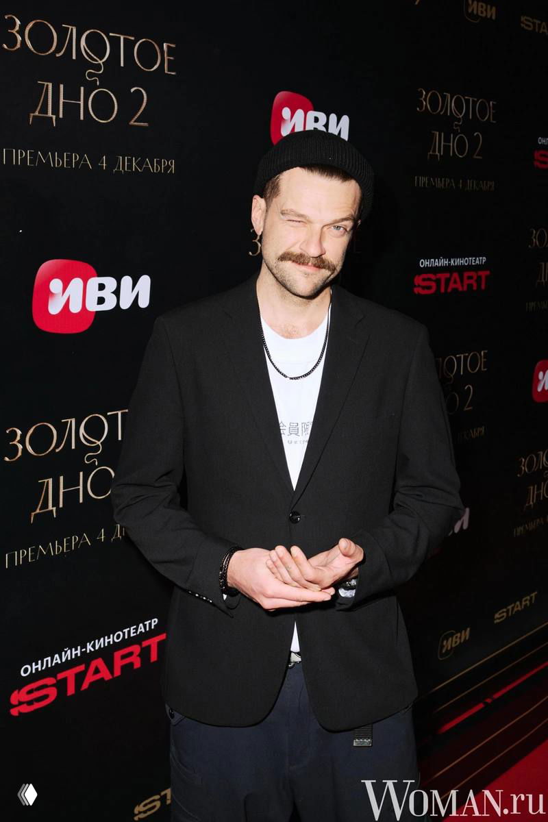 Портрет Кирилла Нагиева на фоне баннера «Золотое дно 2»: актёр в пиджаке и шапке на красной дорожке премьеры.