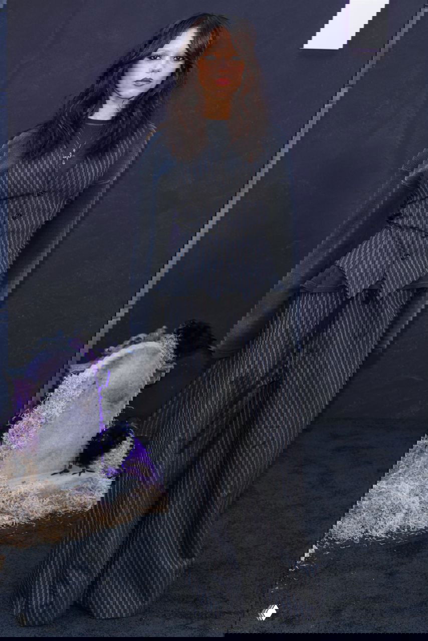 Дженна Ортега в полосатом жилете и широких брюках позирует на чёрном ковре мероприятия в поддержку сериала «Уэнсдей» в Лос‑Анджелесе.