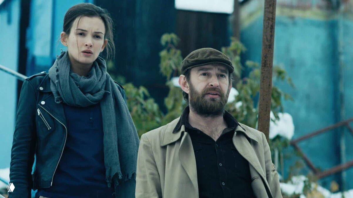 Кадр из сериала «Метод»: мужчина и женщина в уличной зимней сцене, герои разговаривают на фоне городского пейзажа и снега.