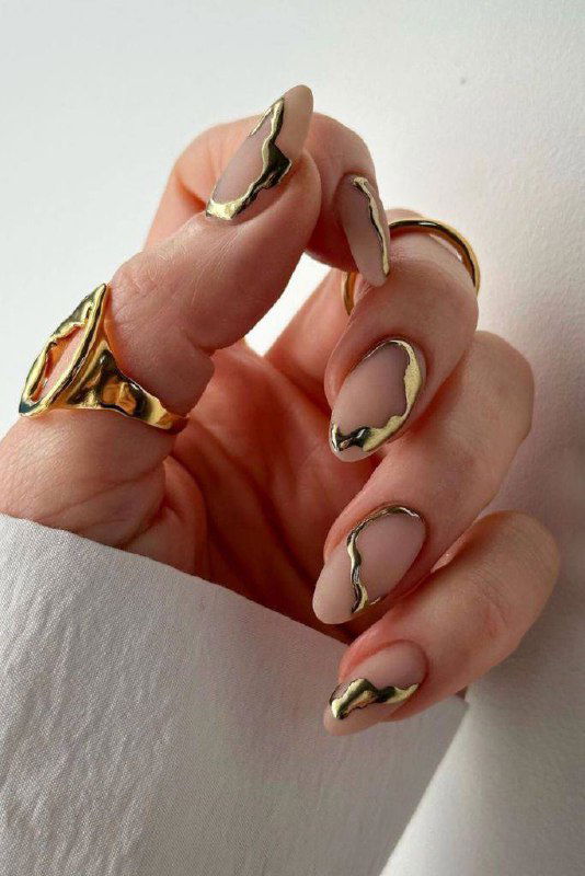 Нюдовый маникюр с золотыми абстрактными элементами, матовая основа и металлические линии создают эффект «стеклянной дымки» и премиум-стиля.
