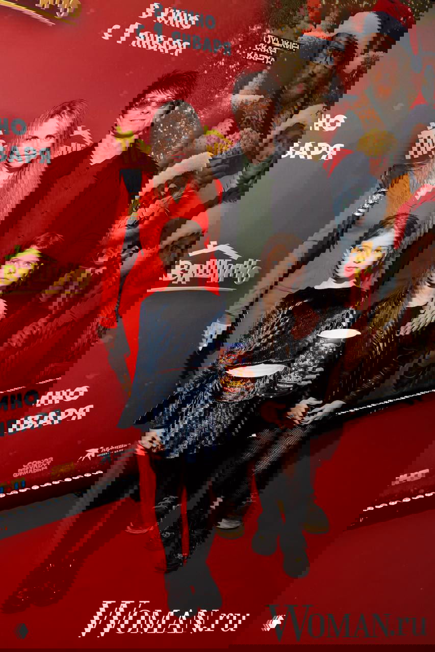 Семья с двумя дочками позирует на фоне постера семейного фильма «Простоквашино» во время премьеры на красной дорожке.