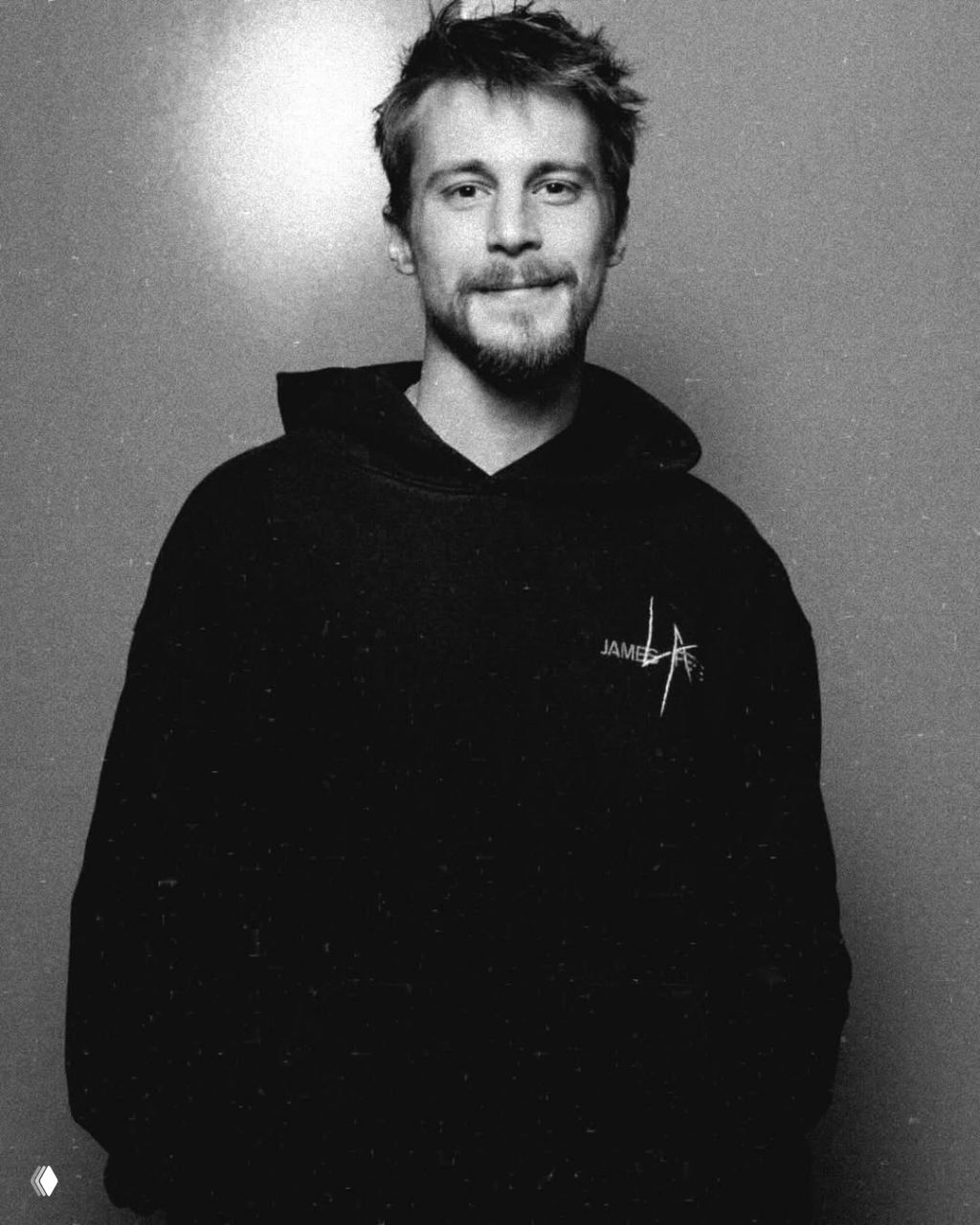 Чёрно‑белый портрет Ивана Янковского в толстовке, кадр в среднем плане с мягким освещением, спокойная улыбка и нейтральный фон.