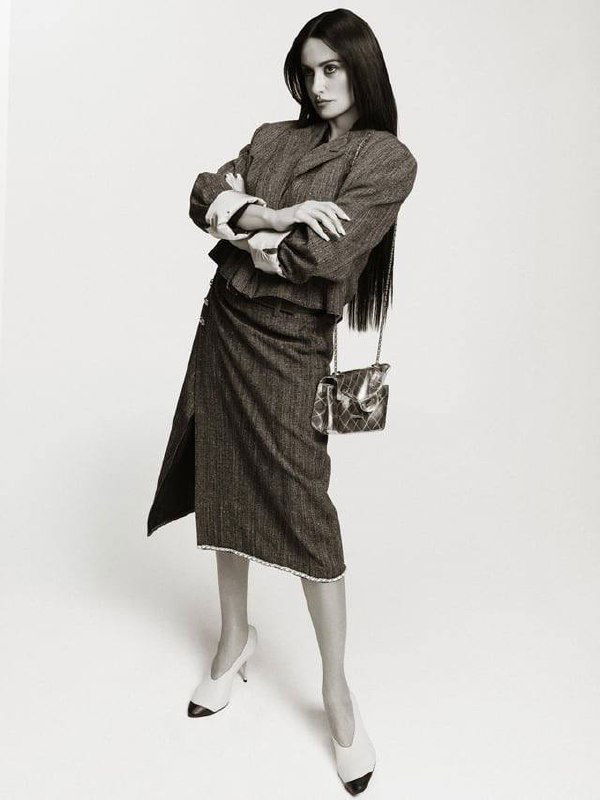 Черно-белый снимок в полный рост: женщина в костюме и юбке-миди, сумка через плечо, стилизованный ретро-образ.