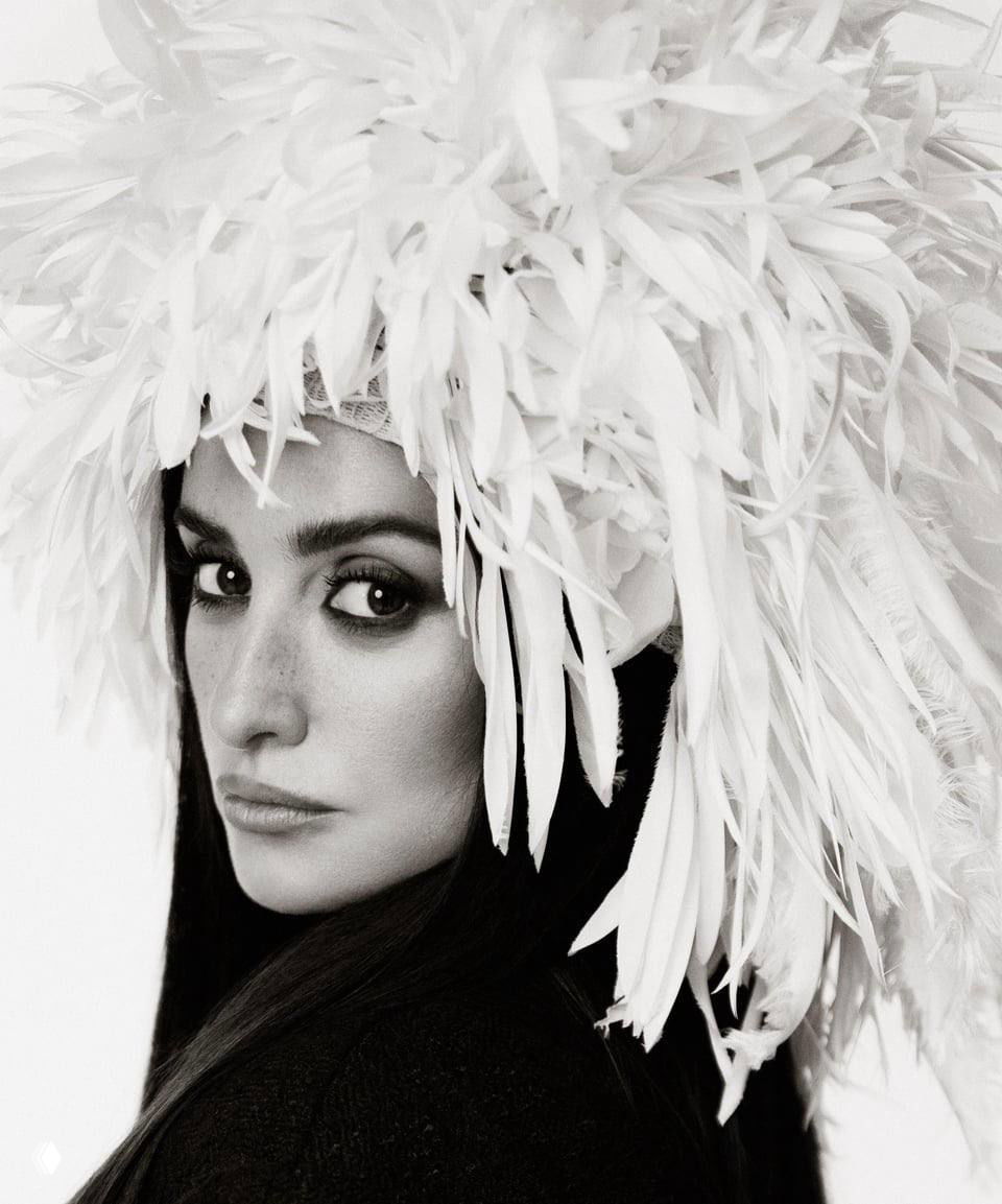 Крупный черно-белый портрет: женщина в головном уборе из перьев, выразительные глаза и контрастный свет студийной съёмки.