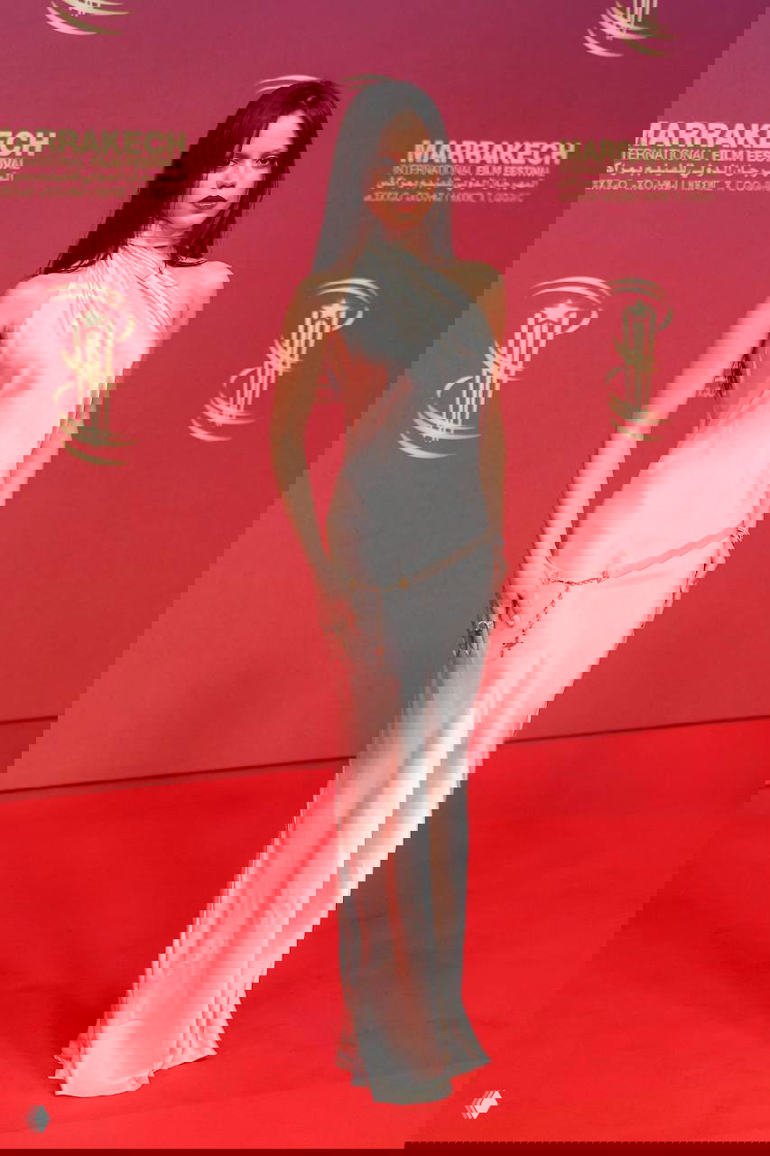 Дженна Ортега в длинном белом шёлковом платье на красной дорожке фестиваля, полный рост, видно драпировку и лёгкие украшения в образе