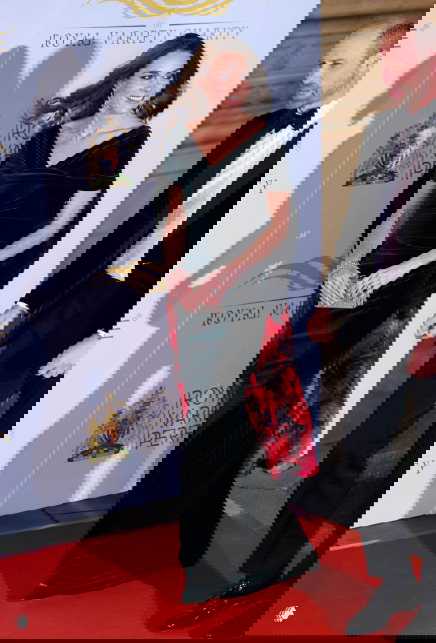 Кэтрин в длинном тёмно‑зелёном бархатном платье идёт по красной дорожке Royal Variety; вид в полный рост, платье с развевающимся подбоем.