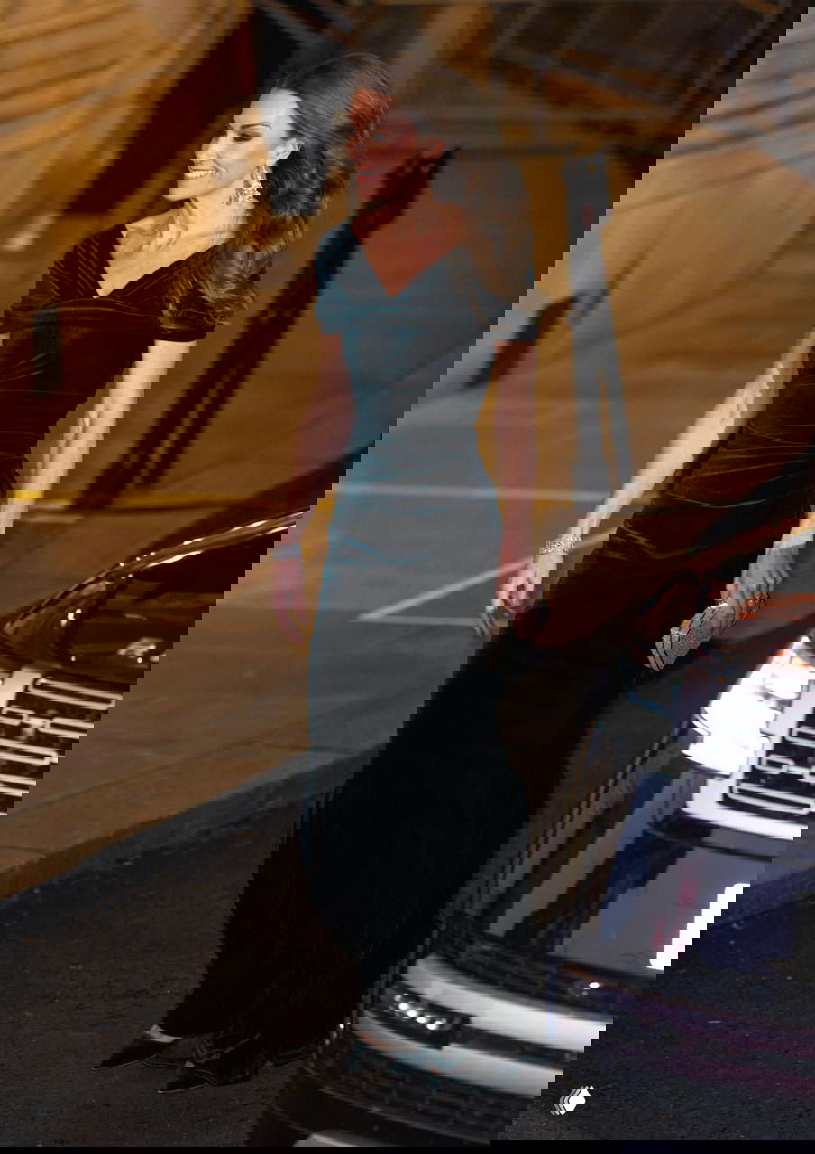 Кейт Миддлтон в тёмно‑зелёном бархатном облегающем платье у входа на мероприятие; красный ковер, сумочка и украшения заметны в кадре.