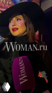 Жасмин в чёрной шляпе и выразительным макияжем; боковой портрет с логотипом Woman.ru и фиолетовым микрофоном в кадре, интервью на мероприятии.