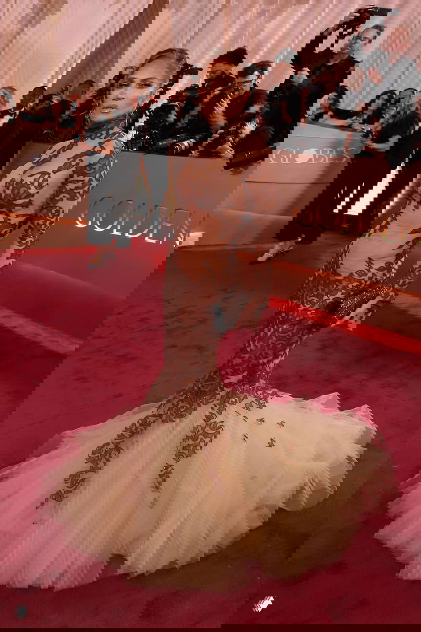 Дженнифер Лопес на красной дорожке «Золотого глобуса 2026» в платье с тюлевой нижней частью и коричневой вышивкой, общий план и фотографы.