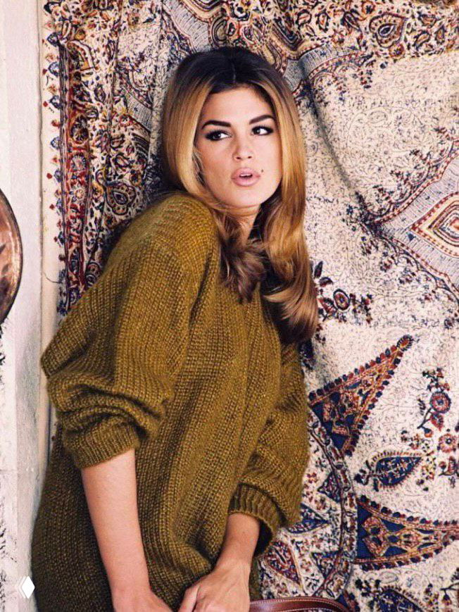 Портретная архивная фотография модели в тёплом вязаном свитере на фоне декоративного ковра, естественный макияж, атмосфера 1990‑х.