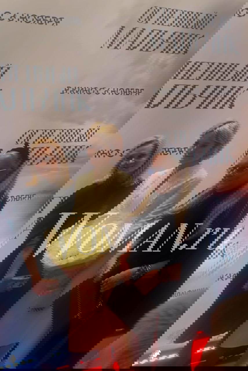 Группа женщин позирует перед фотозоной с постером «Огненный мальчик»: букет цветов, фотозона и надпись о дате релиза видны на заднем плане.