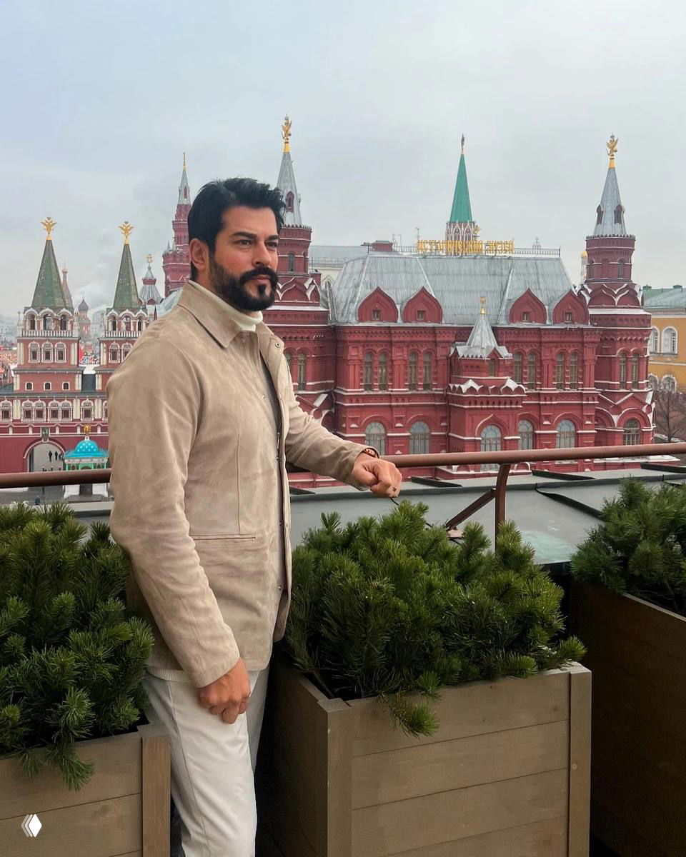 Мужчина в лёгком пальто на террасе с видом на исторические здания Москвы, стильный образ, архитектурный фон и урбанистическая атмосфера.