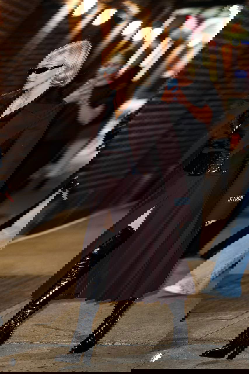 Актриса в длинном тёмном пальто и высоких лаковых ботфортах, смелый вечерний стритстайл с акцентом на фактуру и силуэт