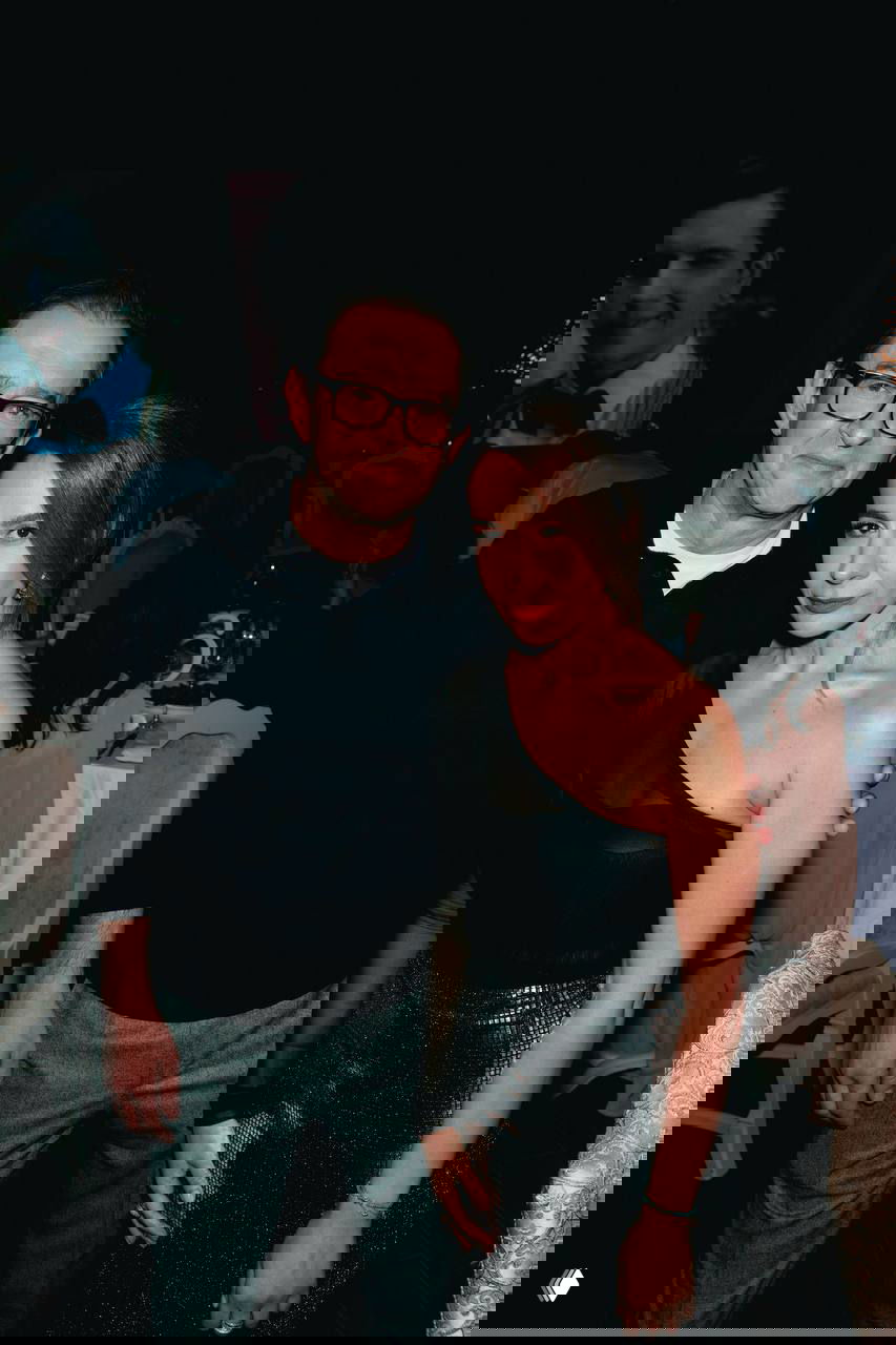 Мужчина и женщина в вечерних нарядах позируют в зале с тёплым освещением; кадр передаёт атмосферу торжественного ужина на благотворительном вечере.