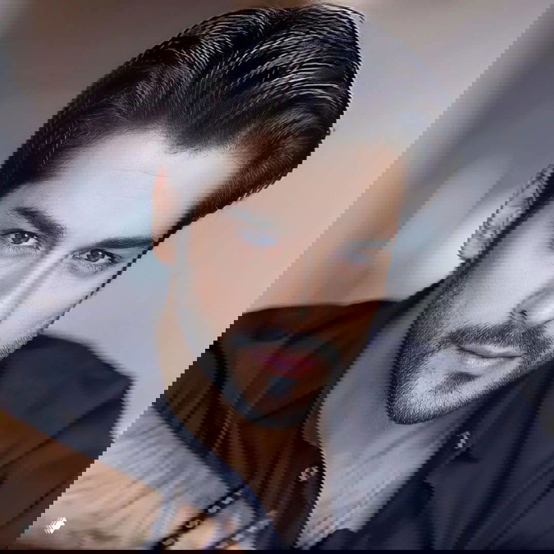 Крупный план лица мужчины в студийном портрете: подчёркнутые черты, аккуратная причёска, лёгкая щетина и выразительный взгляд в камеру.