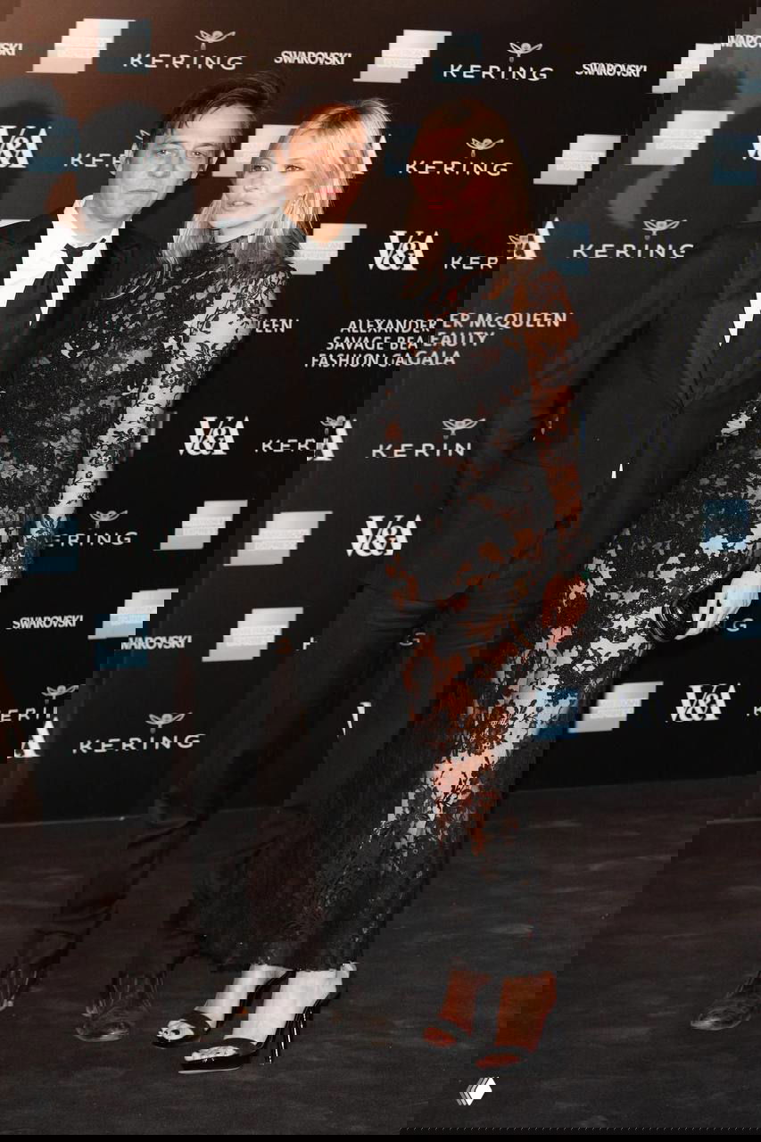 Кейт Мосс и приглашённый гость на красной дорожке в вечерних нарядах: чёрное кружевное платье, фотоколл и благородная атмосфера мероприятия.