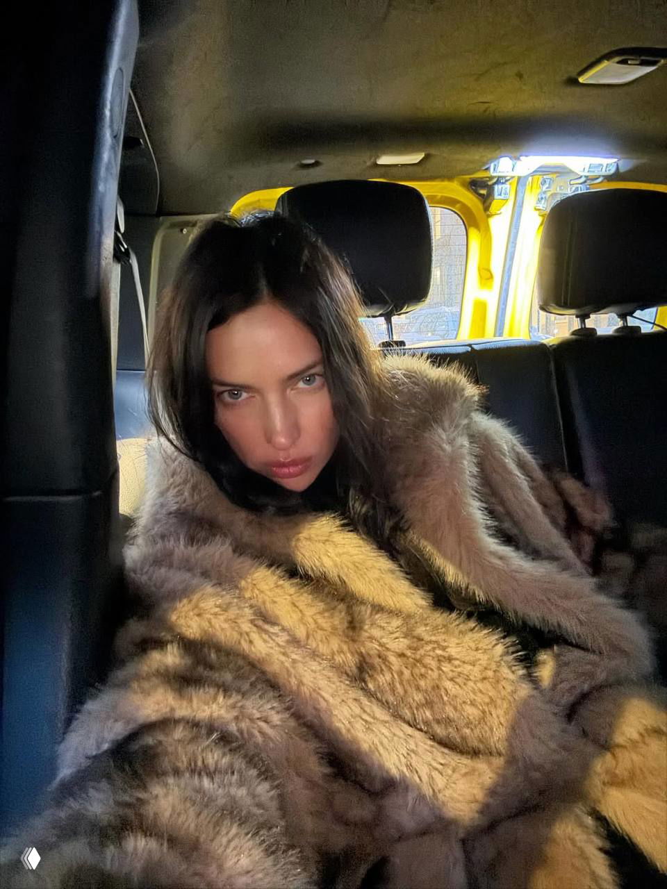 Женщина в тёмной меховой шубе, селфи в салоне автомобиля — портретный кадр с модной атмосферой и холодным светом.