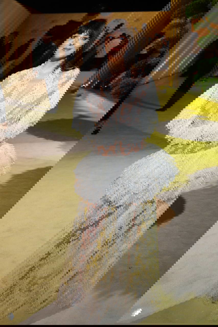 Дакота Джонсон в белом прозрачном кружевном платье Chloé с рюшами и глубоким декольте на гала-ужине «Женщины в кино», общий план, светлый ковер