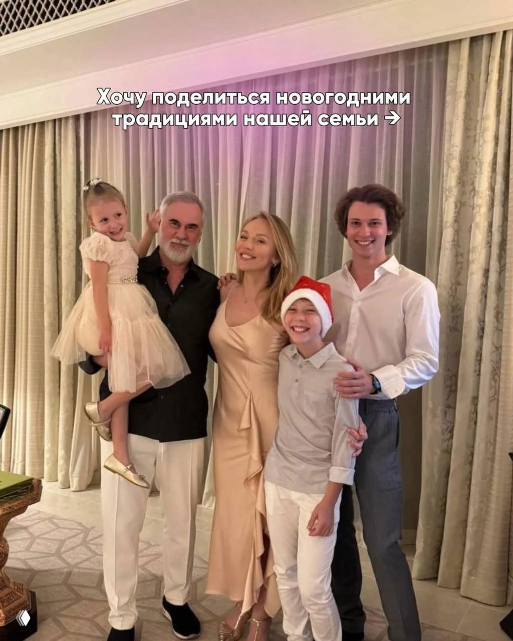 Альбина Джанабаева с Валерием Меладзе и детьми на семейном портрете в гостиной — праздничная, тёплая домашняя атмосфера и улыбки всех членов семьи.