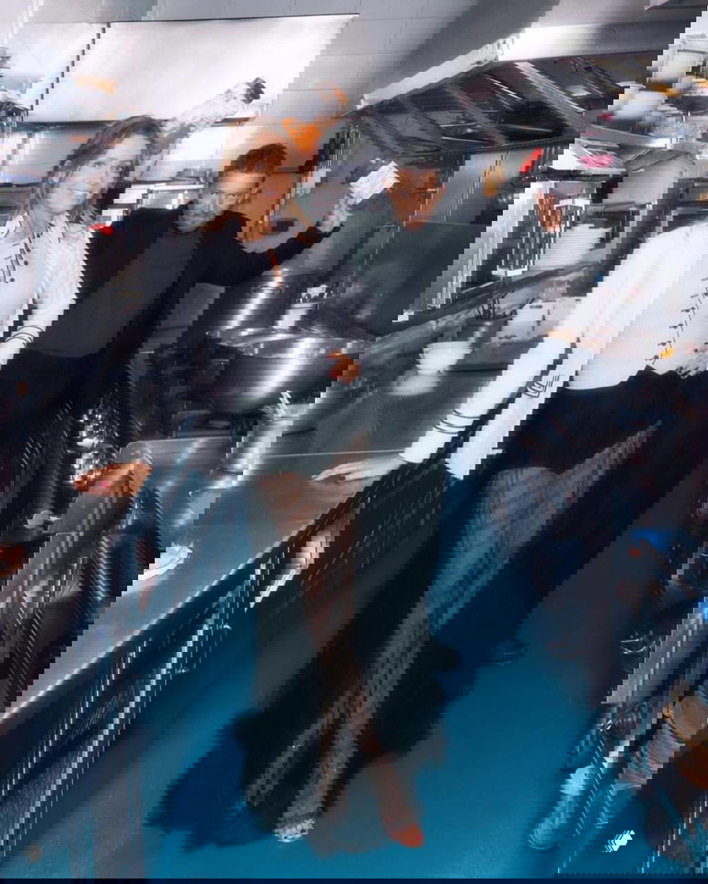 Интерьерный кадр в кухне и профессиональной плитой: мужчина и женщина в стиле высокой моды среди кухонных деталей и реквизита.