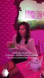 Аврора Киба в розовой обстановке сидит за столом с чашкой и десертом; на кадре видна надпись-цитата о муже: «Муж — как кость...»