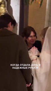 Невеста и родственница улыбаются в момент после церемонии: женщина держит ребёнка, размеренное тёплое настроение в мечети.