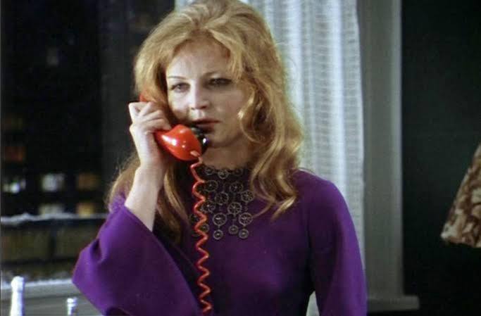 Кадр фильма: молодая Галя в фиолетовом платье говорит по красному телефонному аппарату в интерьерной сцене.