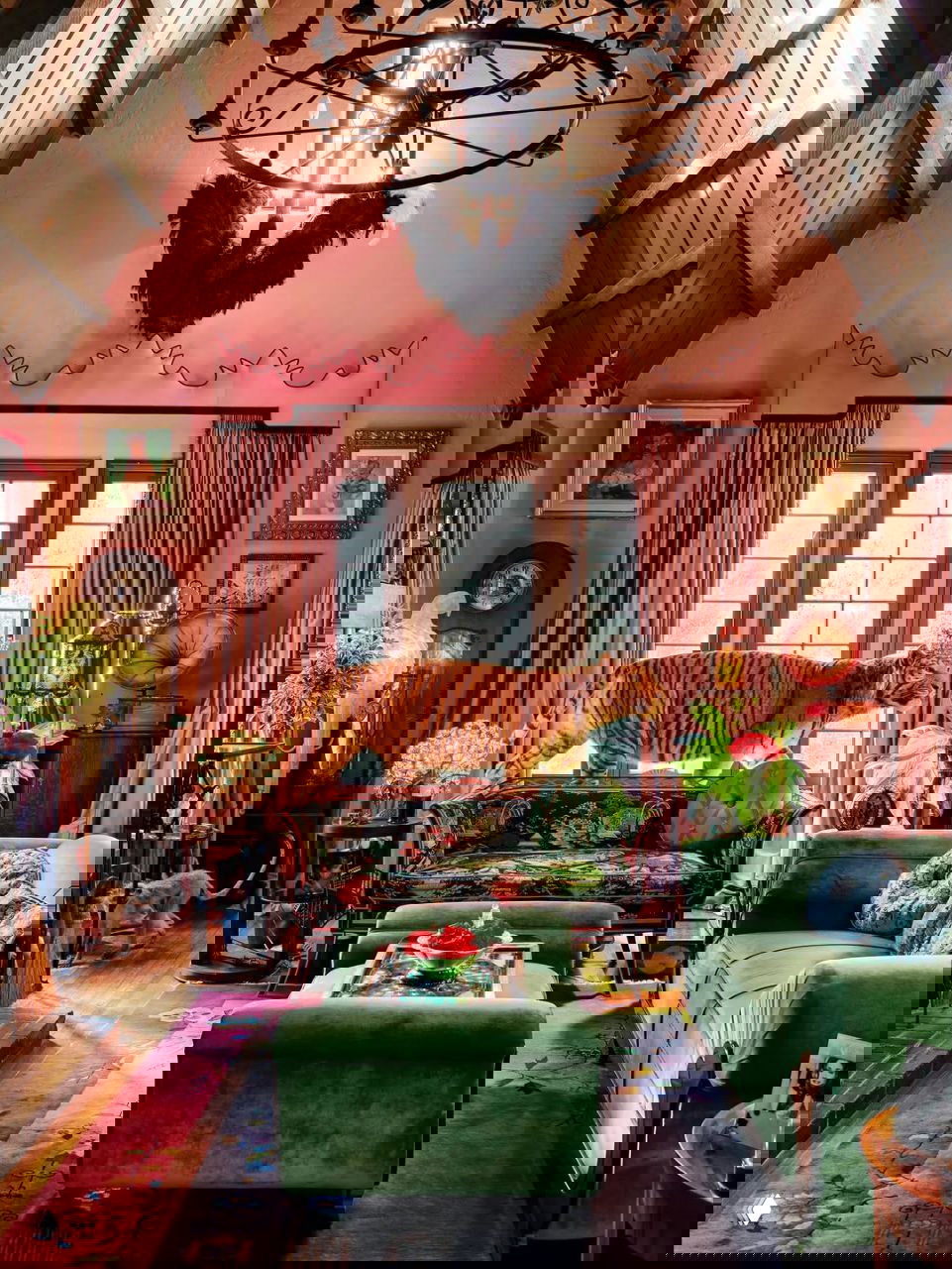 Яркая гостиная с высокими сводчатыми потолками, розовыми шторами, зелёной мебелью и королевской эксцентричной декорацией интерьера