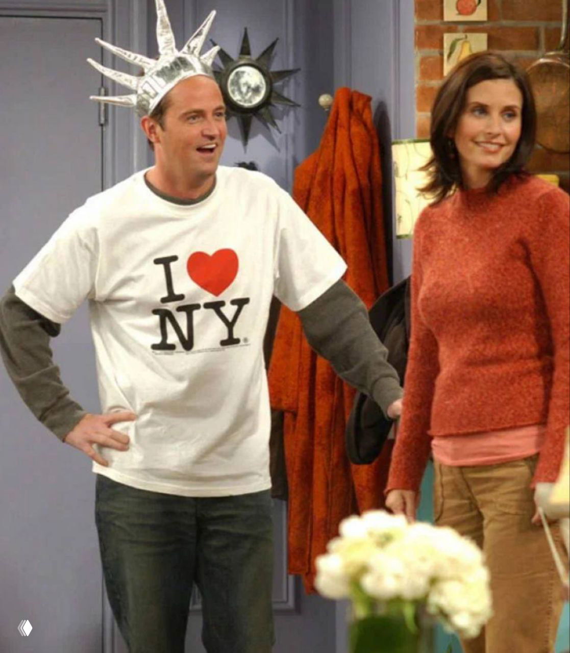 Кадр из эпизода «Друзья» — Мэттью Перри в футболке с принтом «I ♥ NY» рядом с актрисой, лёгкий комедийный эпизод шоу.
