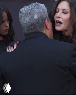 Кадр с моментом приветствия: Кэтрин Зета‑Джонс обнимает кого‑то, рядом Дженна Ортега — запечатлён момент общения за сценой на мероприятии.