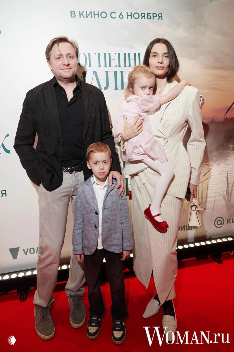 Артём Михалков с женой и детьми позируют на красной дорожке премьеры фильма «Огненный мальчик» перед рекламным баннером. Фото: Woman.ru