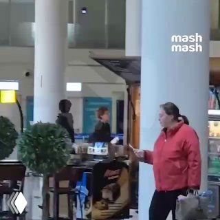 Лариса Гузеева в красной куртке в терминале аэропорта, идет мимо кафе и пассажиров — кадр из видео в Тбилиси.